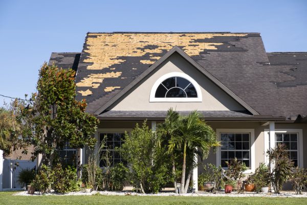 Wind damaged house roof with missing asphalt shingles after hurricane Ian in Florida. Repair of home rooftop concept.
